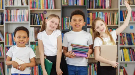 Four children holding stack of books in library m 2026 01 08 23 02 06 utc