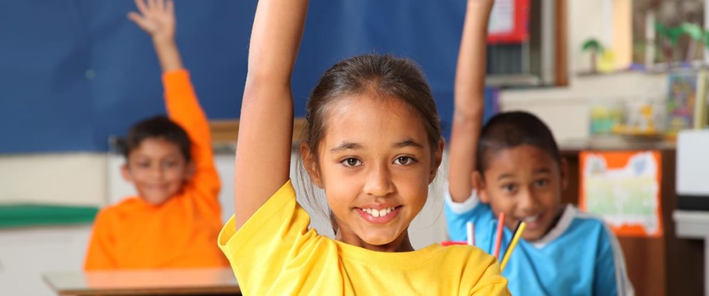 Children raising their hands in a classroom