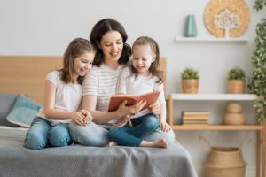 young mother reading a book to her daughters, encourage kids to read