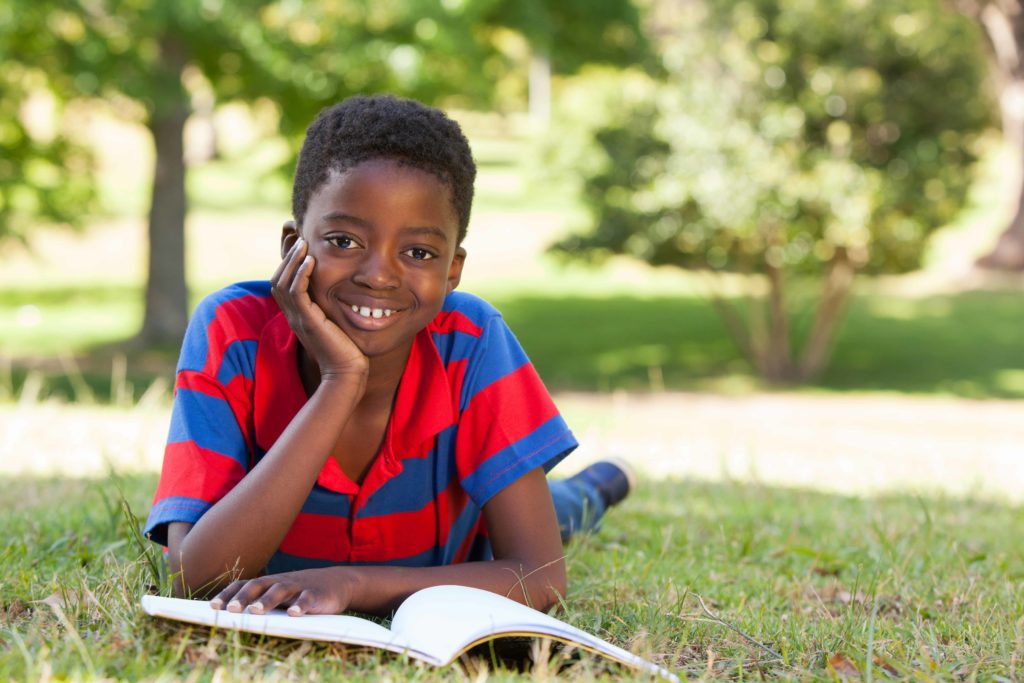 Little boy reading in the park; how to get more books to build bigger libraries