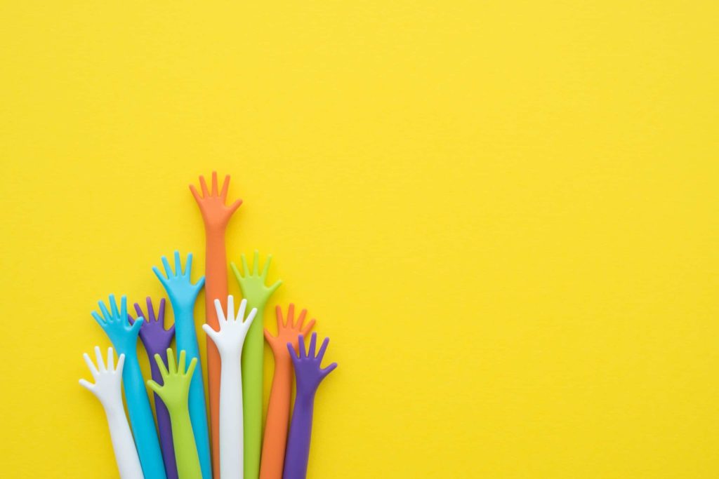Raised hands of multiple bright colors