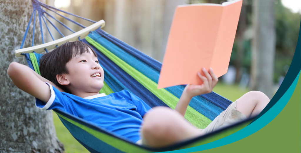 Young boy with book in hammock outside of school - independent reading practice - Kids Read Now